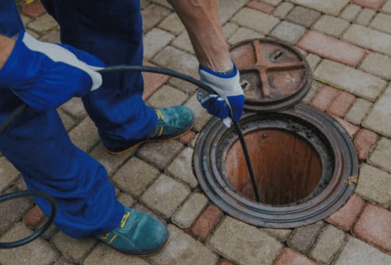 A worker from Wooley Water Sewer Trenchless is cleaning and inspecting a sewer line in Carroll, OH.